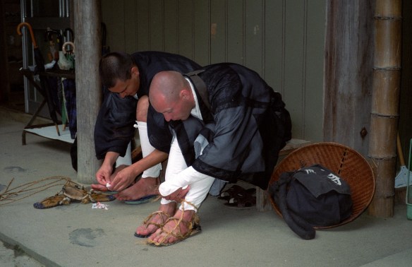 Two monks tying on their sandals for takuhatsu (ritual begging)