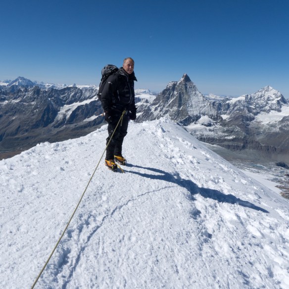 Me on the summit of Breithorn with the Matterhorn in the distance behind.